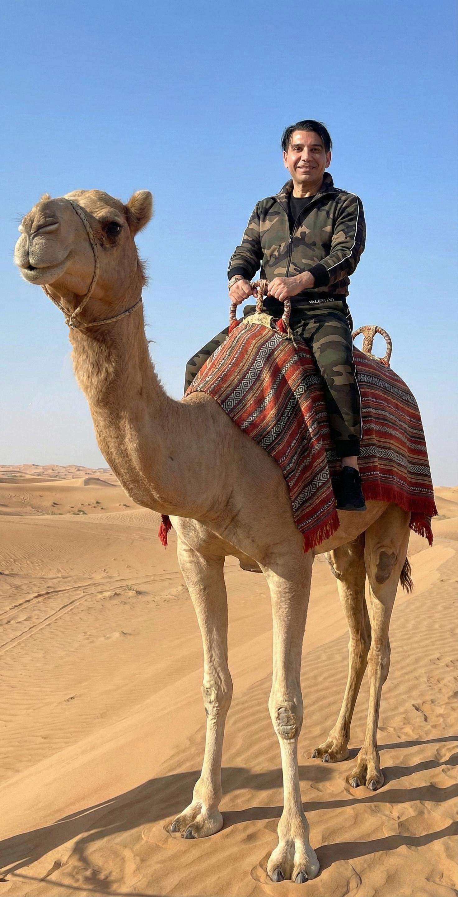 Fred Khalilian riding camel in Dubai desert — UAE international adventures